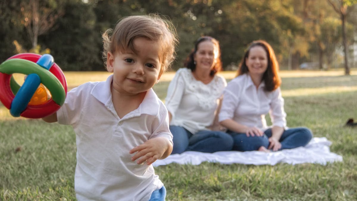 A joyful family enjoying a picnic in the park with a playful toddler in the foreground.