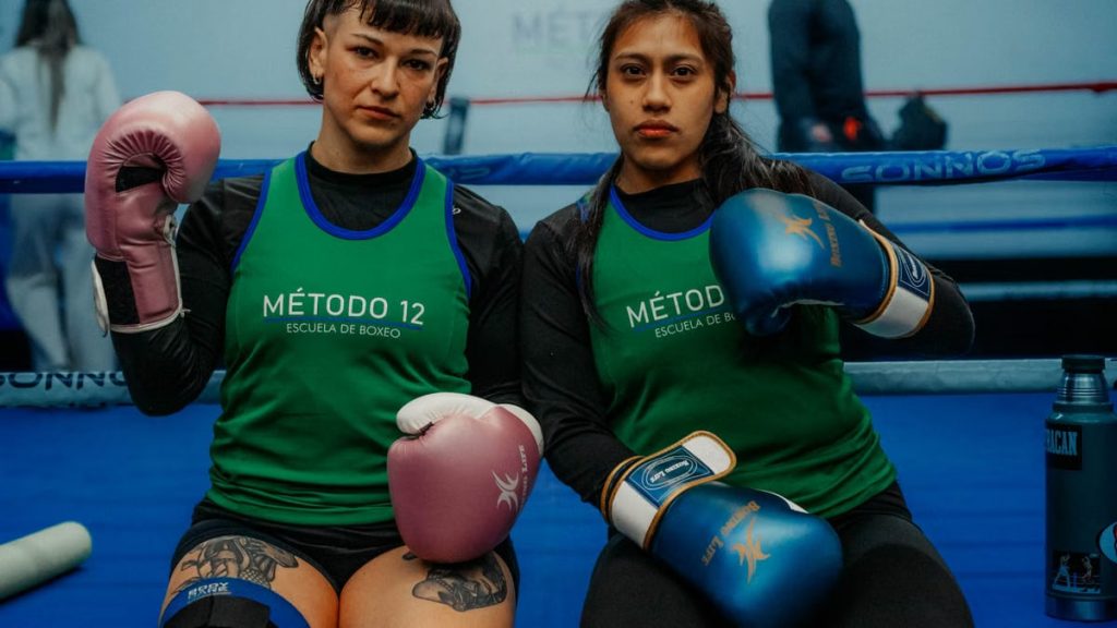 Two female boxers in a Buenos Aires gym, ready for training, showcasing determination.