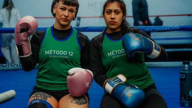 Two female boxers in a Buenos Aires gym, ready for training, showcasing determination.
